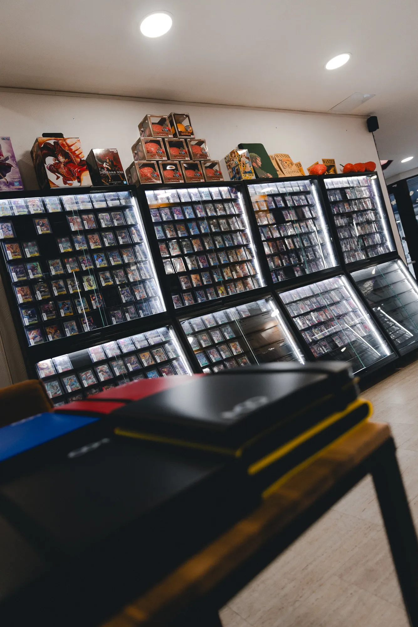 Le mur de vitrines de cartes Pokémon et One Piece de la boutique
